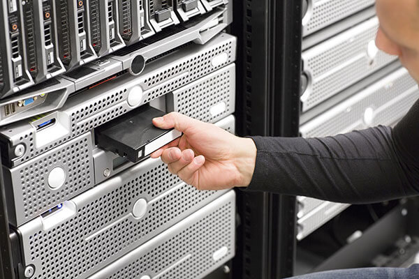 IT administrator puts magnetic tape cassette into data center memory system.